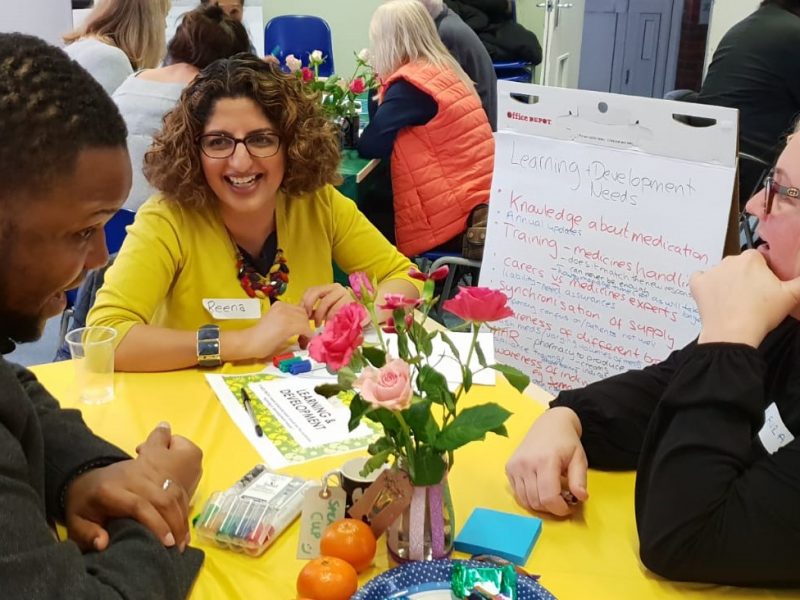 Three people around a table talking at an engagement event in Sutton
