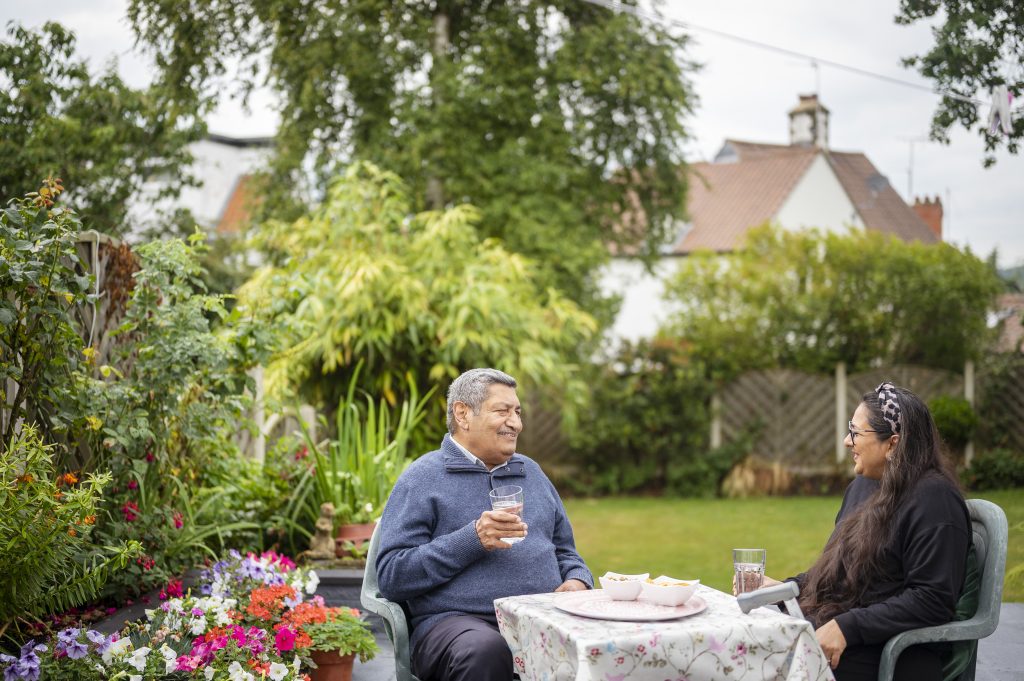 Two people sitting in a private garden having a drink