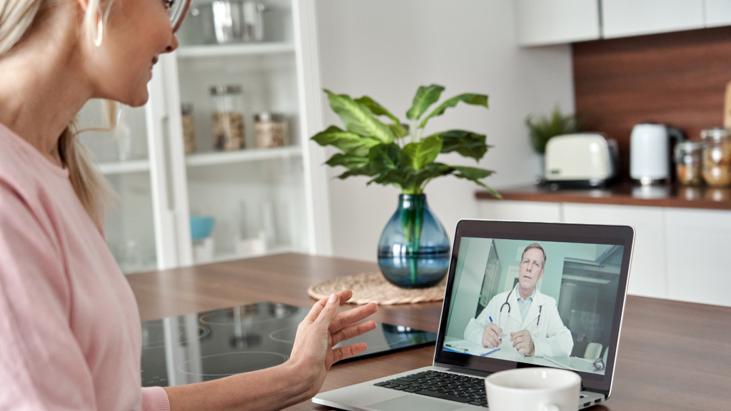 Woman engaging in virtual GP call sitting in her kitchen.