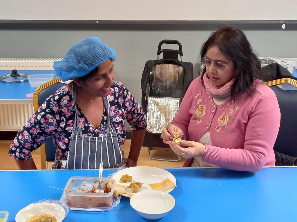 Two women sat at a table preparing food