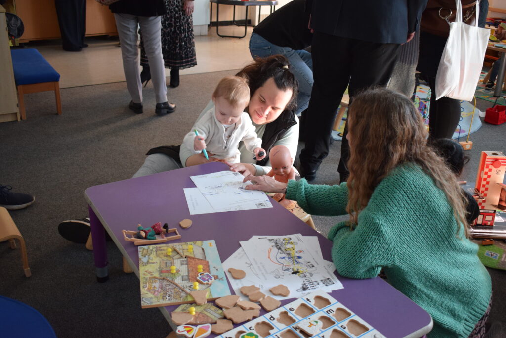 A mother holding her child while she draws at the Family Hub.