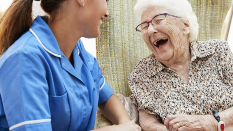 A nurse and an elderly patient laughing