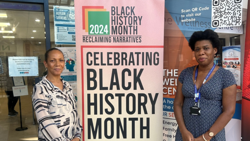 Two women standing in front of a Black History Month Banner