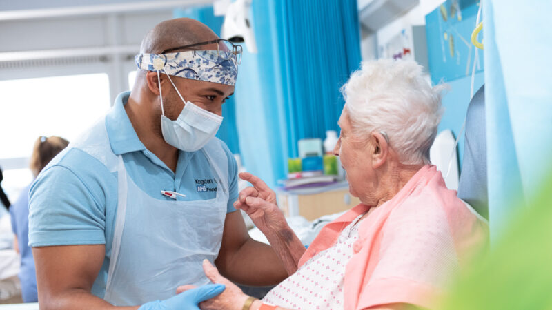 A nurse talking to a patient in her bed at Kingston Hospital