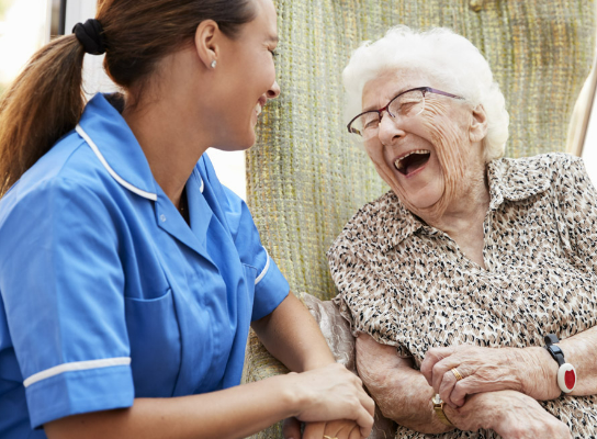 A nurse and an elderly patient laughing