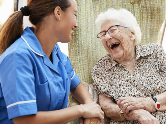 A nurse and an elderly patient laughing