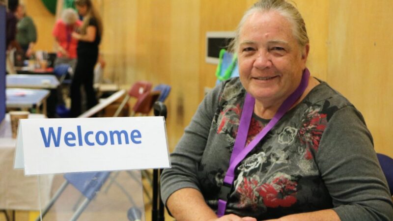 Woman with welcome sign at Roundshaw Wellbeing event in Sutton