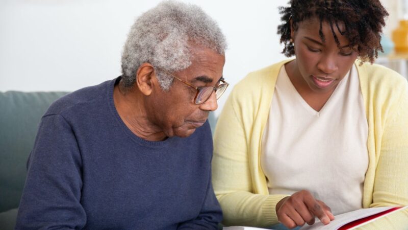 carers support - older man and younger woman look at a book