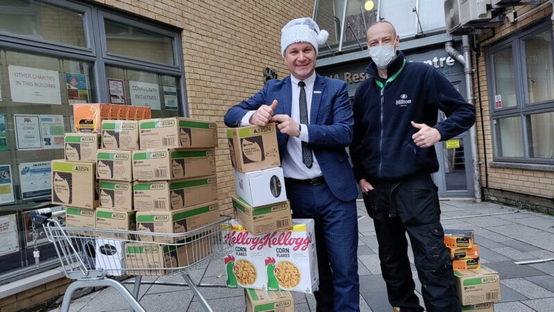 Two men smiling with food donations for a food bank.