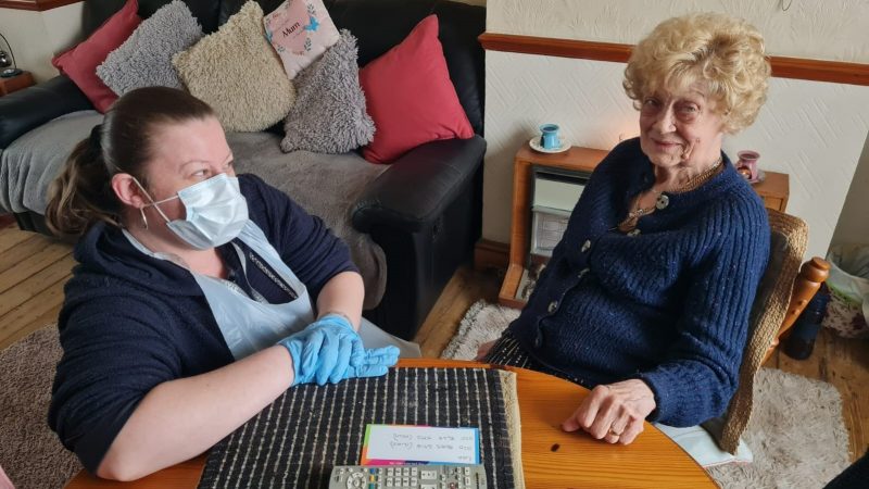 A health and wellbeing co-ordinator with a patient in her home
