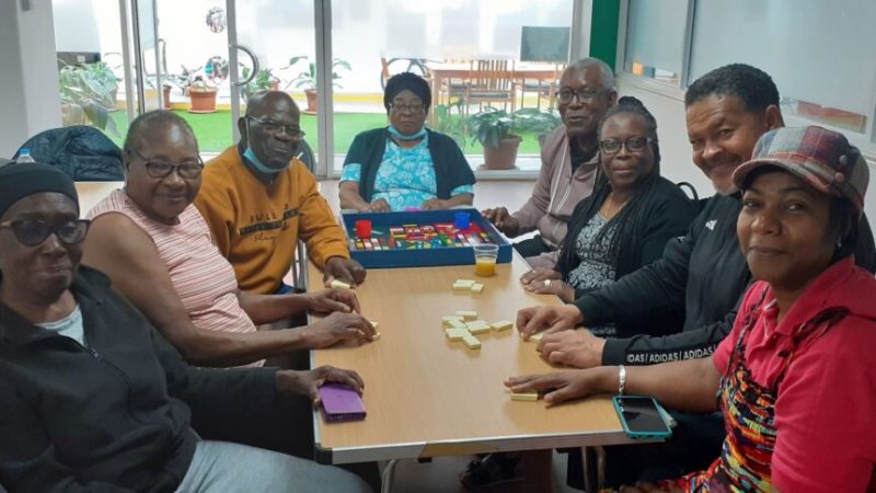 A grouip of eight people sat around a table at the Ethnicity and Mental Health Improvement Project in Tooting