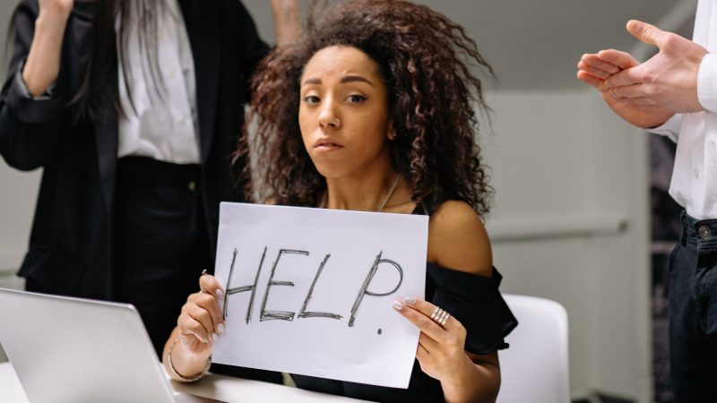 Woman at work with 'help' sign